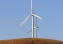 Two wind turbines on a hill. Photo: Unsplash/Rory Tucker