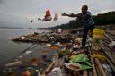 A Hindu devotee throws flowers and plastic bags into river Brahmaputra in Gauhati, India (AP)