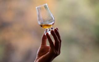 A person swirling a glass of whisky. Credit: PA