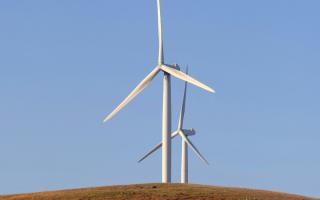 Two wind turbines on a hill. Photo: Unsplash/Rory Tucker